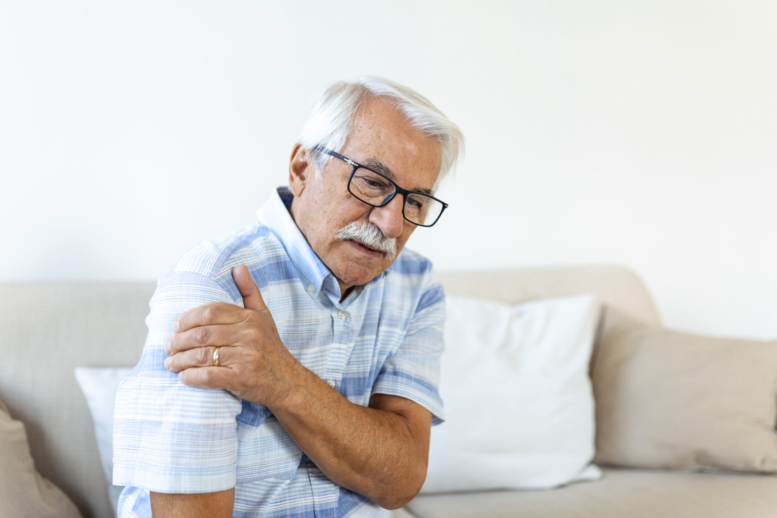 Old senior man with shoulder pain. Upset senior elder man feel sudden back pain muscles ache tension injury at home, grandfather touching shoulder having osteoarthritis arthritis